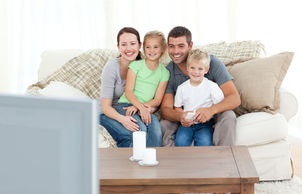 Adorable family watching television together sitting on the sofa at home