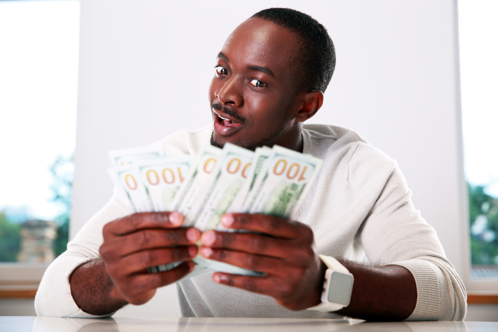 Portrait of a happy african man holding US dollars