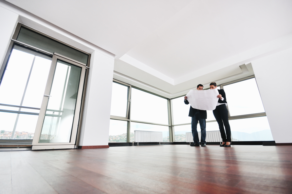 young architect group in big bright modern new apartment looking blueprints and building plans