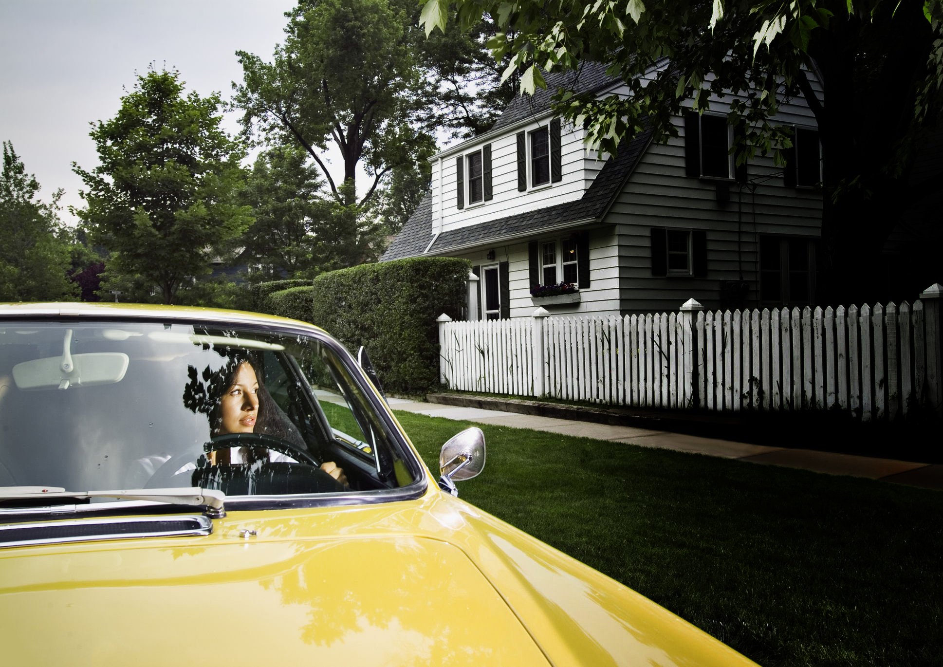 Woman-driving-yellow-car-looking-at-houses_edited-2